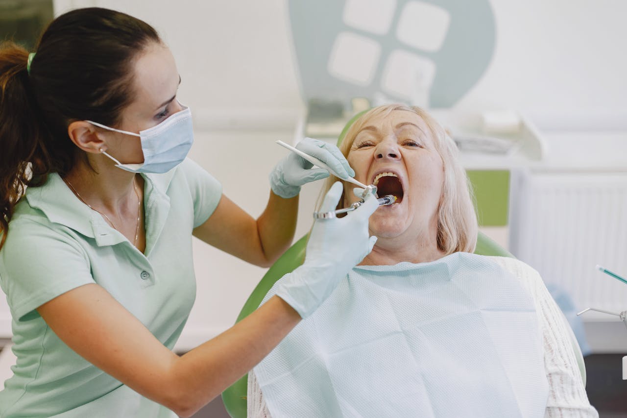 A female dentist examines a senior woman patient in a dental clinic setting.